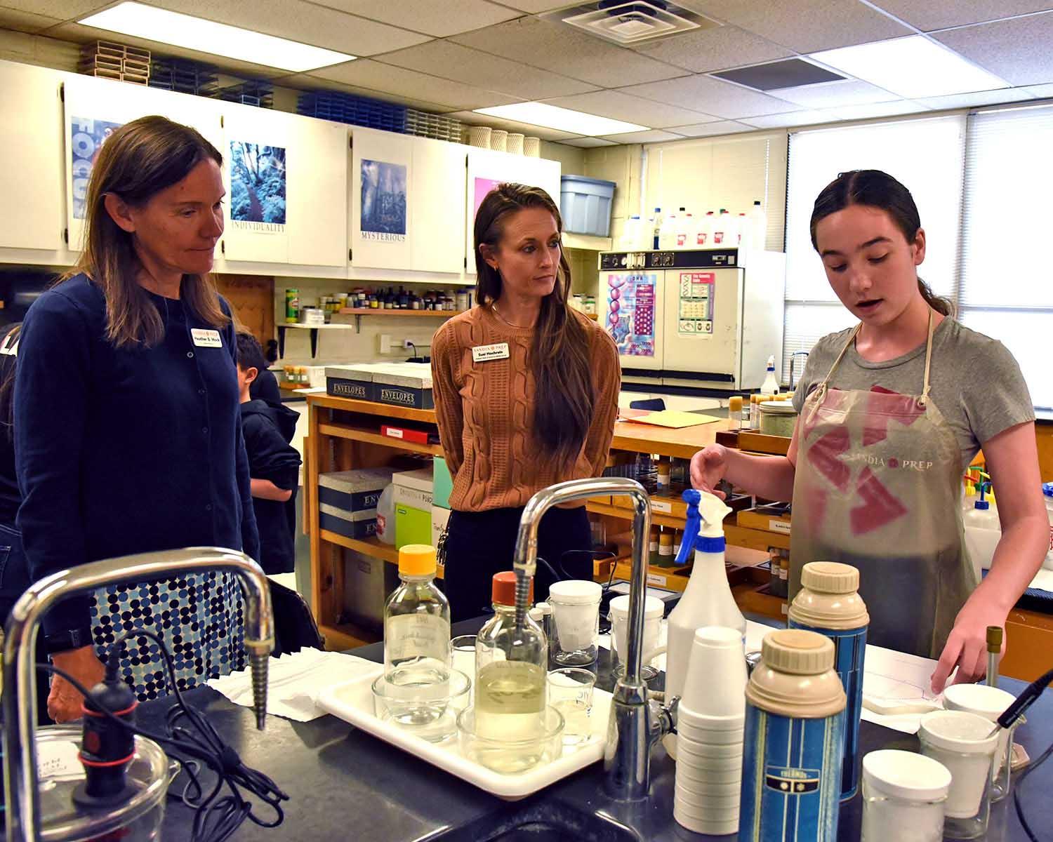 Head of School and Assistant Head of School talk with student in chemistry lab 